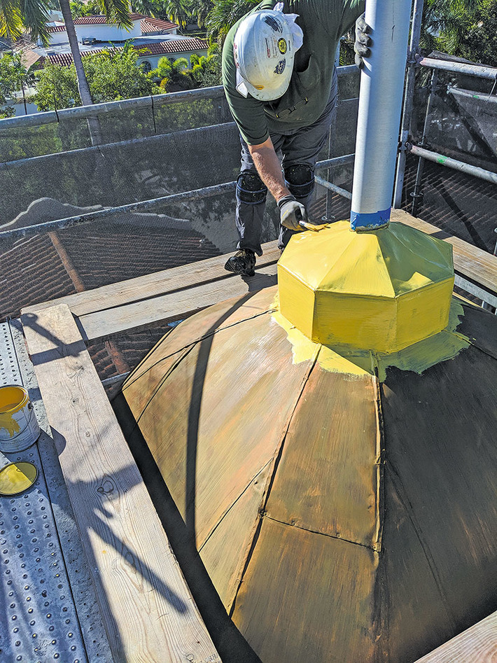 A worker preps the copper dome to receive adhesive.